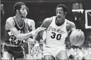  ?? RUSTY KENNEDY, FILE/AP PHOTO ?? Jamaal Wilkes of the Golden State Warriors, left, tries to keep 76ers forward George McGinnis from getting closer to the basket during the first half of an NBA game on Nov. 25, 1975, in Philadelph­ia.