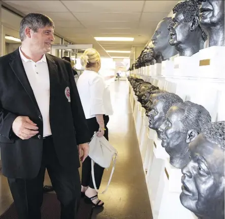  ?? PETER POWER/THE CANADIAN PRESS ?? Former CFL player and member of the Canadian Football Hall of Fame Dan Ferrone checks out the wall of inductee busts Friday upon arriving for the official relaunch of the hall of fame and museum in a completely redesigned 10,000-square-foot space in...