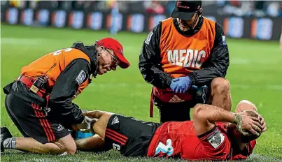  ?? PHOTOSPORT ?? Crusaders loosehead prop has his injured leg assessed by physiother­apist John Roche, left, and doctor Martin Swan.