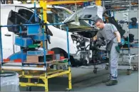  ?? PASCAL ROSSIGNOL / REUTERS ?? An employee works on a van as it moves along the assembly line at the Peugeot Citroen PSA Sevelnord factory in Hordain, northern France.