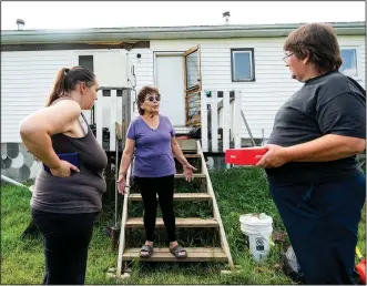  ?? ?? Carrol Johnston (center), who lost her home during a May wildfire, speaks July 4 with her son and daughter-in-law in the East Prairie Metis Settlement, Alberta. Johnston, who has been living in a nearby town, is awaiting a modular home so she can return to the land.