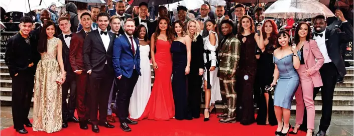  ??  ?? Winning line-up: The cast of shelter under umbrellas last night outside the Royal Albert Hall, where the musical won seven Olivier awards