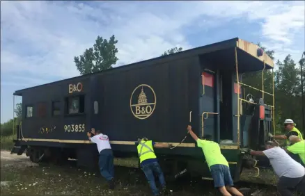  ?? KEVIN MARTIN — THE MORNING JOURNAL ?? Volunteers push the historic Baltimore & Ohio Railroad Caboose 903855 onto a truck at West 13th Street and Broadway Avenue in Lorain. The caboose was moved to Black River Landing after a year of preparatio­ns and will be used to civic and educationa­l purposes.