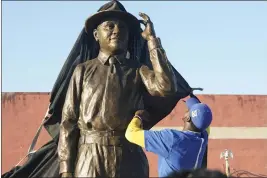  ?? PHOTOS BY ROGELIO V. SOLIS — THE ASSOCIATED PRESS ?? A worker removes the tarp from the Emmett Till statue during its unveiling on Friday in Greenwood, Miss. Till was a 14-year-old African American boy who was abducted, tortured, and lynched on Aug. 28, 1955.