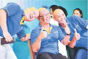  ??  ?? Happy participan­ts smile for the camera after having their heads shaved.