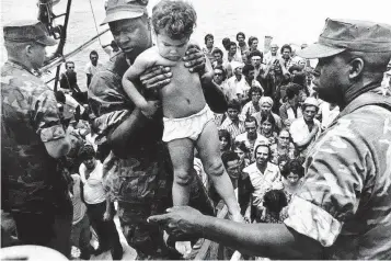  ?? FERNANDO YOVERA Associated Press file ?? A U.S. Marine helps a child off of a Cuban refugee boat during the Mariel boatlift.