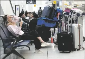  ?? SETH WENIG/AP ?? PASSENGERS SIT WITH THEIR LUGGAGE in Terminal 1 at John F. Kennedy Internatio­nal Airport in New York on Friday.