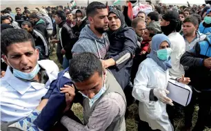 ?? AFP ?? An injured Palestinia­n woman is carried by protesters as they run for cover during clashes with Israeli security forces near the border with Israel, east of Khan Yunis, in the gaza Strip. —