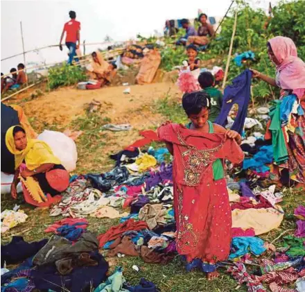  ?? [ FOTO REUTERS ] ?? Kanak-kanak perempuan pelarian Rohingya memilih pakaian yang disumbangk­an oleh penduduk tempatan dicox ’s Bazar, Bangladesh.