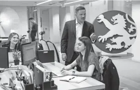  ?? PABLO MARTINEZ MONSIVAIS/AP ?? Alex Slater, managing director of Clyde Group, a public relations firm, talks with employees Grace Haring, left, and Allison Baer, in Washington.