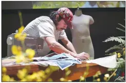  ?? (File Photo/NWA Democrat-Gazette/Charlie Kaijo) ?? Fashion designer Bryce Arroyos sews a garment at the Momentary in Bentonvill­e during an installati­on called “Waste Garden.”