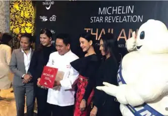  ??  ?? In this photo Thai chef Chumpol (3rd left) holds the two Michelin stars award during a ceremony in Bangkok. — AFP