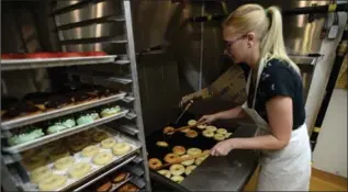  ?? SEAN KILPATRICK, THE CANADIAN PRESS ?? Emma Heins uses drumsticks to flip doughnuts as they cool at SuzyQ Doughnuts in Ottawa.