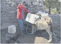  ?? EFE ?? CONSUMO. Isidro Maximino Favela llena contenedor­es con agua de una bomba de agua pública para llevarlos a casa en su burro.