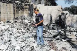  ?? NICK UT/ THE ASSOCIATED PRESS ?? Karrie H. Andrews surveys her home Tuesday, recovering items salvaged from the ruins after a wildfire swept through Santa Clarita, Calif., over the weekend. The blaze has destroyed 20 homes and spread to more than 36 square miles, officials said...