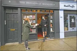  ??  ?? Tom, shop manager of Broadway Bookshop, hands off a book order to a customer June 18 outside the shop in Broadway Market, Hackney, in east London. The business started a website in June and converted to collect and delivery to cope with the lockdown measures due to the coronaviru­s outbreak.
(AP/Alberto Pezzali)