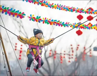  ??  ?? A child wearing a face mask on a ride at a fair in Longtan Park in Beijing yesterday