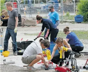  ??  ?? Volunteers clean what could be salvaged from the destroyed Green Fools Theatre building in Calgary’s Erlton neighbourh­ood on Tuesday.