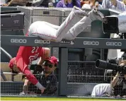  ?? DAVID ZALUBOWSKI/AP ?? Cincinnati Reds third baseman Brandon Drury tumbles over the rail for the third-base well while pursuing a pop foul off the bat of Colorado Rockies’ Elias Diaz in the second inning Sunday in Denver.