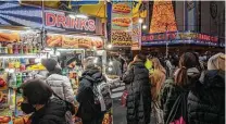  ?? Christophe­r Occhicone / Bloomberg ?? Tourists wait in line to purchase food from a street vendor in New York. Grocery prices are easing from record highs.