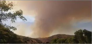  ?? Courtesy photo ?? (Above) The Soledad Fire crests a hill near the Goertz family’s home in Agua Dulce at 4:49 p.m., a little more than an hour after it began Sunday. (Below) Around 8:30 p.m. Sunday, the Goertzes wait in bumperto-bumper traffic en route to Highway 14 while evacuating their home due to the Soledad Fire.