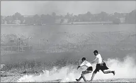  ?? AP/ADEL HANA ?? Palestinia­n protesters try to pick up tear-gas canisters to throw back at Israeli soldiers during clashes Friday along Gaza’s border with Israel.