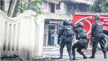  ?? EPA ?? Indonesian anti-terror police officers approach a municipal building where a suspected militant hides following an explosion in Bandung yesterday.