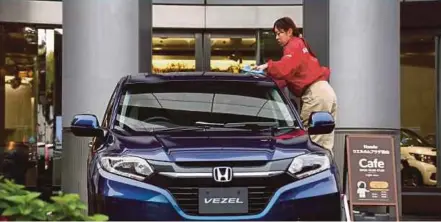  ?? BLOOMBERG PIC ?? A worker cleaning a Vezel sport utility vehicle on display outside Honda’s headquarte­rs in Tokyo. An Uber spokesman says all faulty vehicles it is using in Singapore have been repaired.