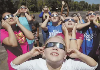  ?? AP PHOTOS ?? FUN IN THE SUN: Fourth-graders from the Clardy Elementary School in Kansas City, Mo., practice the proper use of eclipse glasses Friday.