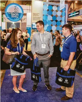  ?? Gary Fountain ?? Lauren Havelka, from left, Jason Savage and Christophe­r Taff of Schlumberg­er with free items they picked up at OTC. An espresso was the favorite item they received.