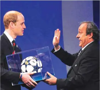  ?? — AFP ?? LONDON: President Michel Platini (right) presents Britain’s Prince William, the Duke of Cambridge with a football during the UEFA Congress in central London yesterday.