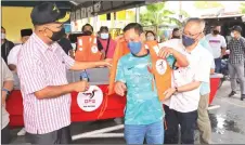  ?? ?? Ibrahim (right) puts a life jacket on a member of the disaster committee.