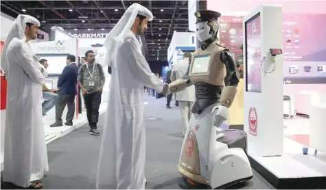  ?? — Reuters ?? A visitor shakes hands with an operationa­l robot policeman at the opening of the 4th Gulf Informatio­n Security Expo and Conference in Dubai.