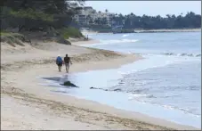  ?? The Maui News / MATTHEW THAYER photo ?? Beach walkers have a stretch of sand in north Kihei nearly to themselves Tuesday morning. Walking for exercise on beaches is a permitted activity amid the stay-athome order.