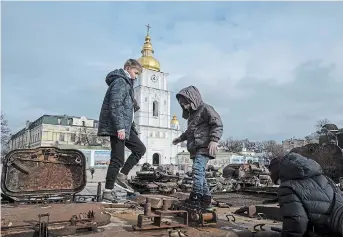  ?? EVGENIY MALOLETKA THE ASSOCIATED PRESS ?? Children stand atop of a destroyed Russian vehicle in the city centre of Kyiv, Ukraine, on Thursday.