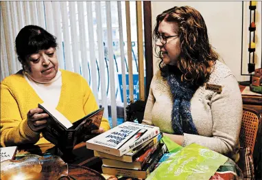  ?? DONNA VICKROY/DAILY SOUTHTOWN ?? Carmen Pedroza, left, looks over new materials from the Oak Lawn Public Library, delivered by staffer Meghan Moran through the facility’s home delivery program.