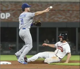 ??  ?? Los Angeles Dodgers second baseman Logan Forsythe throws out Atlanta Braves’ Nick Markakis at first base after forcing out Charlie Culberson (right) at second base during the eighth inning of a baseball game on Saturday, in Atlanta. AP PHOTO/JOHN AMIS