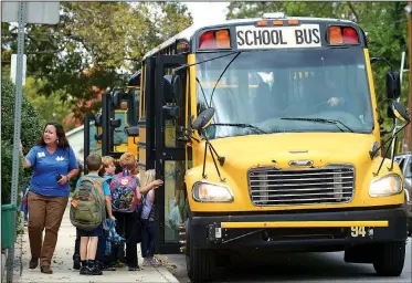  ?? NWA Democrat-Gazette/ANDY SHUPE ?? Ashley McLarty, Washington Elementary School principal, speaks to students Friday as they board buses for home in front of the Fayettevil­le school. The Springdale School District has launched an aggressive campaign to hire eight bus drivers by...