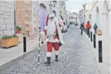  ??  ?? Un ciudadano palestino vestido de Santa Claus camina por una calle casi desierta en Belén.