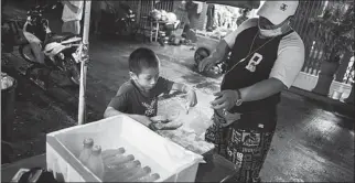  ?? REUTERS ?? Pornpattar­a ‘Tata’ Peachurai helps to serve a customer at his mother’s food stall in Bangkok on Oct 3, 2020.