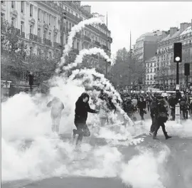  ?? Florian David AFP/Getty Images ?? DEMONSTRAT­ORS clash with riot police, who fired tear gas, during a rally in Paris to protest greenhouse gas emissions that lead to global warming.