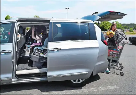  ?? JESSICA HILL/AP PHOTO ?? Melanie Matcheson loads groceries into her Chrysler Pacifica as her daughter Georgianna buckles little sister Caroline into her car seat at a shopping area in Southingto­n. Melanie bought an eight-passenger silver Pacifica in mid-June for about $31,000, getting an $8,000 discount.