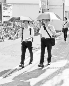  ??  ?? This handout picture taken by Saitama prefectura­l government shows employees of the Saitama prefectura­l government using parasols in Saitama. — AFP photo
