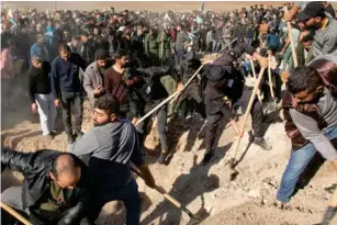  ?? (AFP/Getty) ?? Syrian Kurds in a l- Ma l ikiyah dig graves for 11 peop l e ki ll ed in the airstrikes