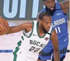  ?? POOL/GETTY IMAGES ?? The Bucks’ Khris Middleton dribbles around the Magic’s James Ennis III during the first game of their series Tuesday.