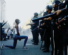  ??  ?? Un manifestan­te si inginocchi­a di fronte agli agenti di polizia durante una protesta a San Jose