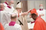  ?? (AFP) ?? Rwandan Archbishop Antoine Kambanda of Kigali (right) receives his biretta hat from Pope Francis (centre) at St. Peter’s Basilica in The Vatican on Saturday.