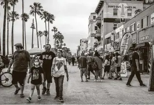  ??  ?? People walk along the Venice Beach boardwalk last week. More than four months into fighting the coronaviru­s in the U.S., the shared sacrifice of millions of Americans suspending their lives has not been enough to beat back the deadly pandemic.