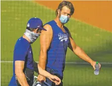  ?? MARK J. TERRILL ASSOCIATED PRESS ?? Los Angeles Dodgers starting pitcher Clayton Kershaw, right, talks with starting pitcher Walker Buehler during the restart of baseball spring training Sunday in Los Angeles.