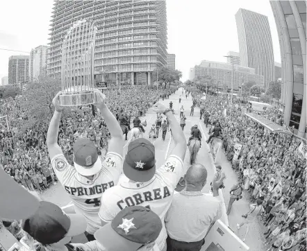  ?? Karen Warren / Houston Chronicle ?? World Series MVP George Springer, left, hoists the World Series trophy alongside teammate Carlos Correa and Mayor Sylvester Turner as they ride atop a firetruck during a parade honoring the MLB champions earlier this month.